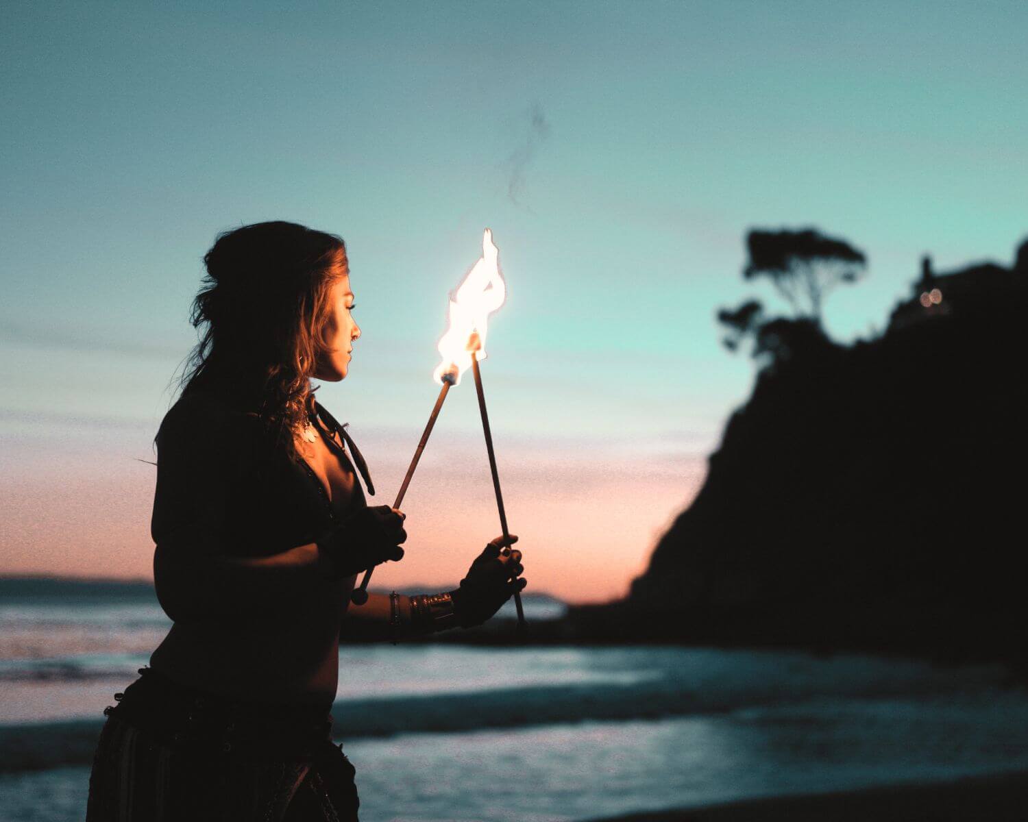 Midlife woman beach sunset holding torches